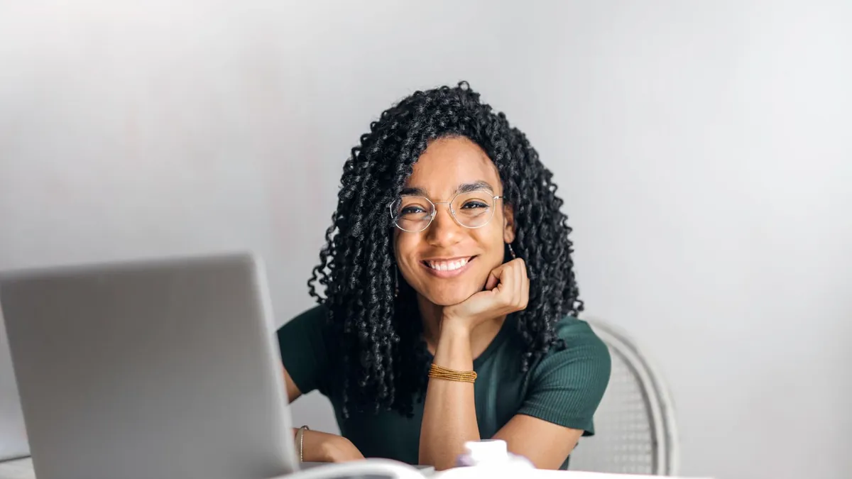 Smiling student studying on a laptop