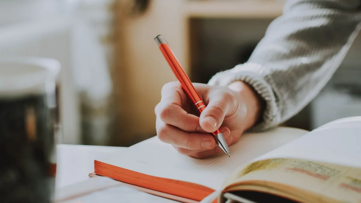 Student writing notes with a pen